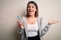 Young beautiful brunette sporty woman drinking bottle of water over isolated white background very happy and excited, winner Royalty Free Stock Photo