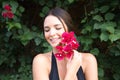 Young beautiful brunette typical Spanish woman dressed in black suit and bouquet of pink flowers near her face. The woman is in Royalty Free Stock Photo