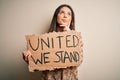 Young beautiful brunette woman asking for union holding banner with unity message serious face thinking about question, very Royalty Free Stock Photo