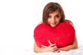 Young beautiful brunette woman in beige dress sitting and holding big red toy heart in hands over white background Royalty Free Stock Photo