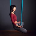 young beautiful brunette woman doing fly yoga. Sitting in hammock with namaste gesture. Wellness concept.