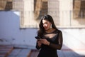 Young, beautiful brunette woman is dressed elegantly in a black dress with transparencies and fancy earrings. The girl is walking