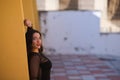 Young and beautiful brunette woman is dressed elegantly in a black dress with transparencies. The girl is leaning against the wall