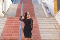 Young, beautiful brunette woman is dressed elegantly in a black dress with transparencies. The girl is walking down a staircase in