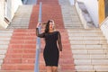 Young, beautiful brunette woman is dressed elegantly in a black dress with transparencies. The girl is walking down a staircase in