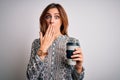 Young beautiful brunette woman drinking glass of takeaway coffe over white background cover mouth with hand shocked with shame for Royalty Free Stock Photo