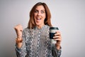 Young beautiful brunette woman drinking glass of takeaway coffe over white background screaming proud and celebrating victory and Royalty Free Stock Photo