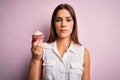 Young beautiful brunette woman eating chocolate cupcake over isolated pink background with a confident expression on smart face Royalty Free Stock Photo