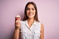 Young beautiful brunette woman eating chocolate cupcake over isolated pink background with a happy face standing and smiling with Royalty Free Stock Photo