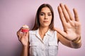 Young beautiful brunette woman eating chocolate cupcake over isolated pink background with open hand doing stop sign with serious Royalty Free Stock Photo