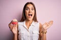 Young beautiful brunette woman eating chocolate cupcake over isolated pink background very happy and excited, winner expression Royalty Free Stock Photo