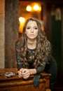 Young beautiful brunette woman in elegant black dress standing near a vintage piano. Sensual romantic lady with long dark hair Royalty Free Stock Photo