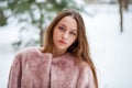 Young beautiful brunette woman in fur coat posing on winter park Royalty Free Stock Photo