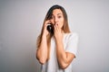 Young beautiful brunette woman having conversation talking on the smartphone cover mouth with hand shocked with shame for mistake, Royalty Free Stock Photo