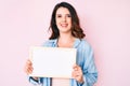 Young beautiful brunette woman holding blank empty banner looking positive and happy standing and smiling with a confident smile Royalty Free Stock Photo