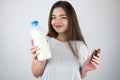 Young beautiful brunette woman holding bottle with milk in one hand and chocolate cookies in another looking satisfied healthy