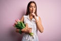 Young beautiful brunette woman holding bouquet of tulips flowers over pink background asking to be quiet with finger on lips Royalty Free Stock Photo