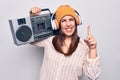 Young beautiful brunette woman listening to music using vintage boombox and headphones smiling with an idea or question pointing Royalty Free Stock Photo