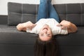 Young beautiful brunette woman lying on the sofa upside down in her appartment, feeling cozy at home