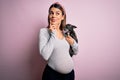 Young beautiful brunette woman pregnant expecting baby holding chihuahua puppy serious face thinking about question, very confused Royalty Free Stock Photo