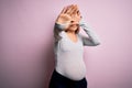 Young beautiful brunette woman pregnant expecting baby over isolated pink background covering eyes with hands and doing stop Royalty Free Stock Photo