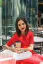 Beautiful brunette woman in red dress drinking coffee in a coffee shop Royalty Free Stock Photo