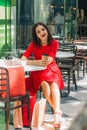 Beautiful brunette woman in red dress drinking coffee in a coffee shop Royalty Free Stock Photo