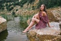 Young beautiful brunette woman sitting by the lake in nature Royalty Free Stock Photo