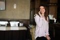 Young beautiful brunette woman sitting near bar counter, talking on the phone and laughing Royalty Free Stock Photo