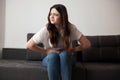 Young beautiful brunette woman sitting on the sofa suffering from extreme pain in stomach looking desperate, healthcare and Royalty Free Stock Photo