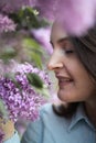 Young beautiful brunette woman is smelling lilac flower blossom in spring time Royalty Free Stock Photo