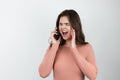 Young beautiful brunette woman standing on  white background having unpleasant conversation on her smarpthone, technology Royalty Free Stock Photo