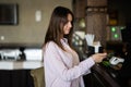 Young beautiful brunette woman using contactless payment, female customer holding mobile phone near nfc technology on counter Royalty Free Stock Photo