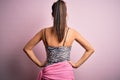 Young beautiful brunette woman on vacation wearing swimsuit over pink background standing backwards looking away with arms on body Royalty Free Stock Photo