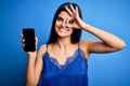 Young beautiful brunette woman wearing blue lingerie holding smartphone showing screen with happy face smiling doing ok sign with Royalty Free Stock Photo