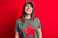 Young beautiful brunette woman wearing cap and t-shirt with red star communist symbol with a happy and cool smile on face