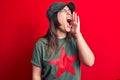 Young beautiful brunette woman wearing cap and t-shirt with red star communist symbol shouting and screaming loud to side with