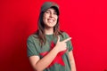 Young beautiful brunette woman wearing cap and t-shirt with red star communist symbol smiling cheerful pointing with hand and