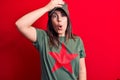 Young beautiful brunette woman wearing cap and t-shirt with red star communist symbol surprised with hand on head for mistake,