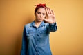 Young beautiful brunette woman wearing casual denim shirt and hair handkerchief doing stop sing with palm of the hand Royalty Free Stock Photo