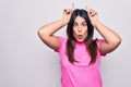 Young beautiful brunette woman wearing casual pink t-shirt standing over white background doing funny gesture with finger over Royalty Free Stock Photo