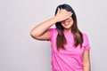 Young beautiful brunette woman wearing casual pink t-shirt standing over white background smiling and laughing with hand on face Royalty Free Stock Photo