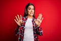 Young beautiful brunette woman wearing casual shirt standing over isolated red background afraid and terrified with fear Royalty Free Stock Photo