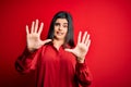 Young beautiful brunette woman wearing casual shirt standing over red background afraid and terrified with fear expression stop Royalty Free Stock Photo