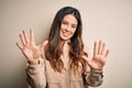 Young beautiful brunette woman wearing casual shirt standing over white background showing and pointing up with fingers number ten Royalty Free Stock Photo