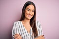 Young beautiful brunette woman wearing casual striped shirt over isolated pink background happy face smiling with crossed arms Royalty Free Stock Photo