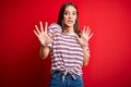 Young beautiful brunette woman wearing casual striped t-shirt standing over red background afraid and terrified with fear Royalty Free Stock Photo