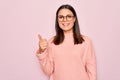 Young beautiful brunette woman wearing casual sweater and glasses over pink background doing happy thumbs up gesture with hand Royalty Free Stock Photo
