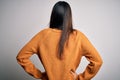 Young beautiful brunette woman wearing casual sweater over isolated white background standing backwards looking away with arms on Royalty Free Stock Photo