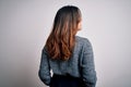 Young beautiful brunette woman wearing casual sweater standing backward over isolated white background